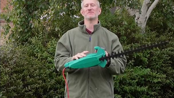 Derek recording a thank you in his garden, holding hedge trimmers